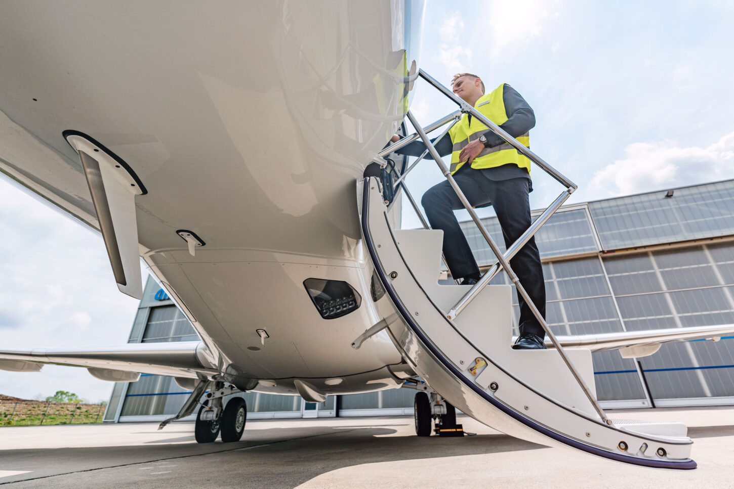 staircase of a parked aircraft from underneath with a security person standing on it